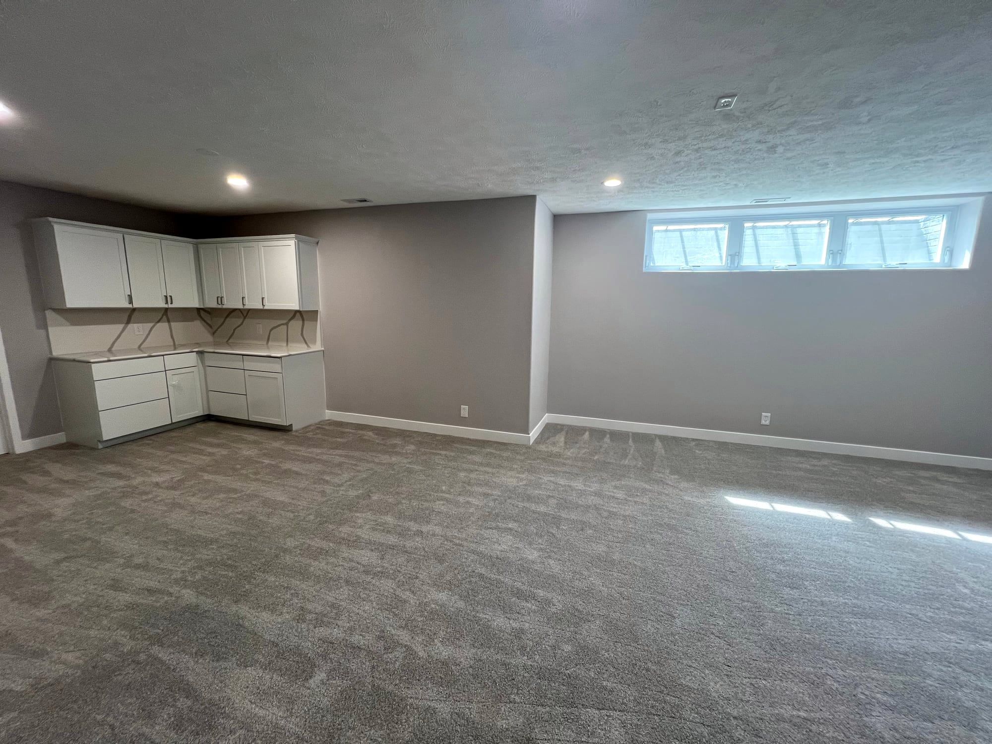 Finished basement with new carpet, recessed lights and wet bar cabinets