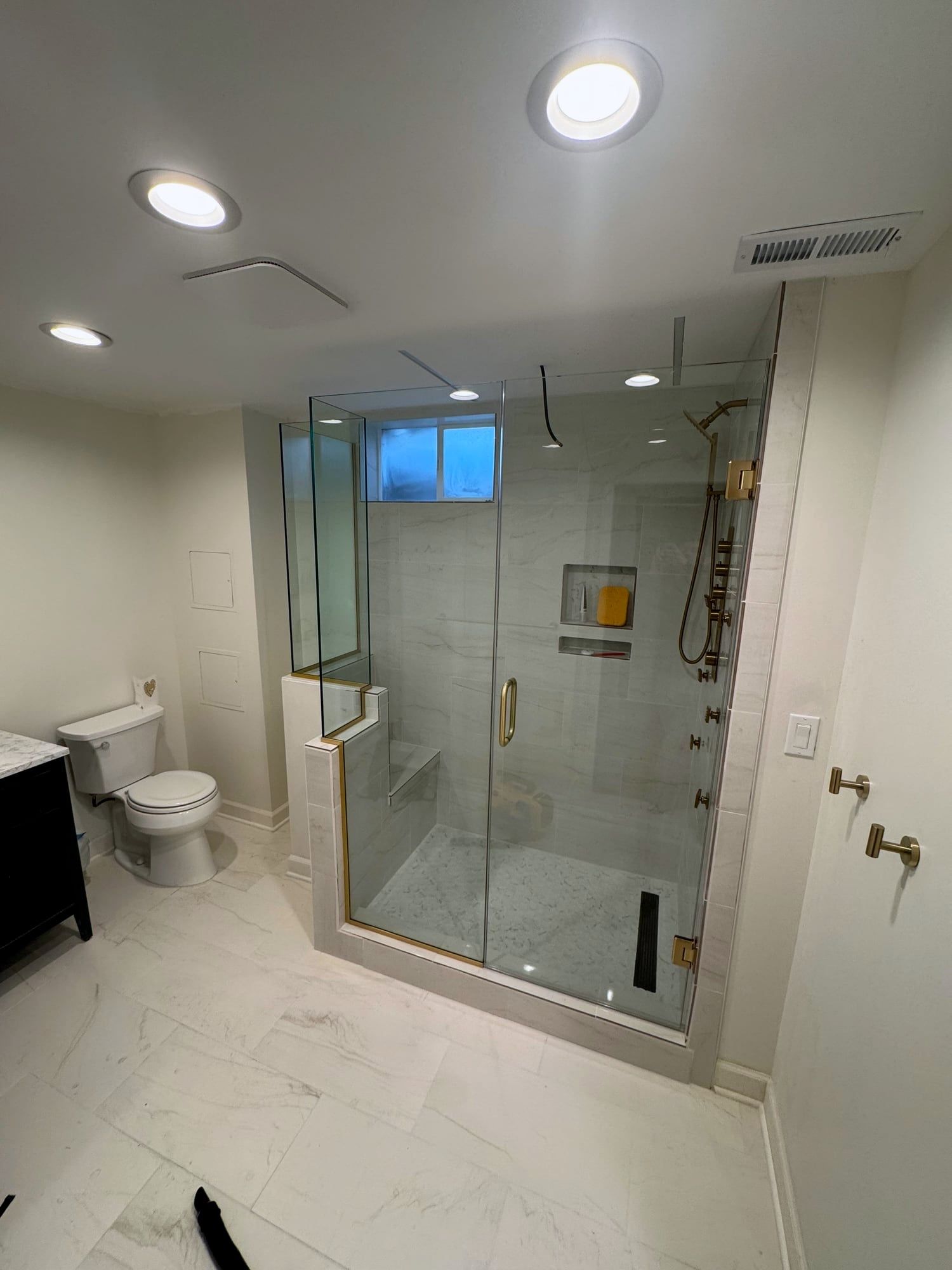 Bathroom with a frameless glass shower, gold fixtures and marble-look tile